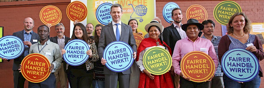 Gruppenbild mit Fair-Handels-Aktiven, die Schilder mit "Fairer Handel wirkt" in der Hand halten